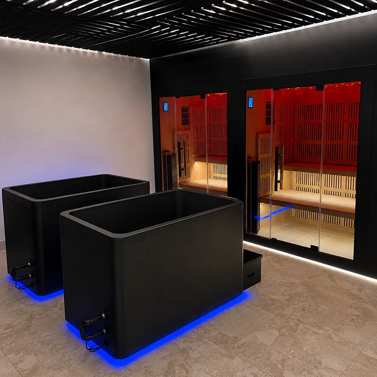 Two black cold plunge tubs with blue floor lighting in front of infrared saunas lit red